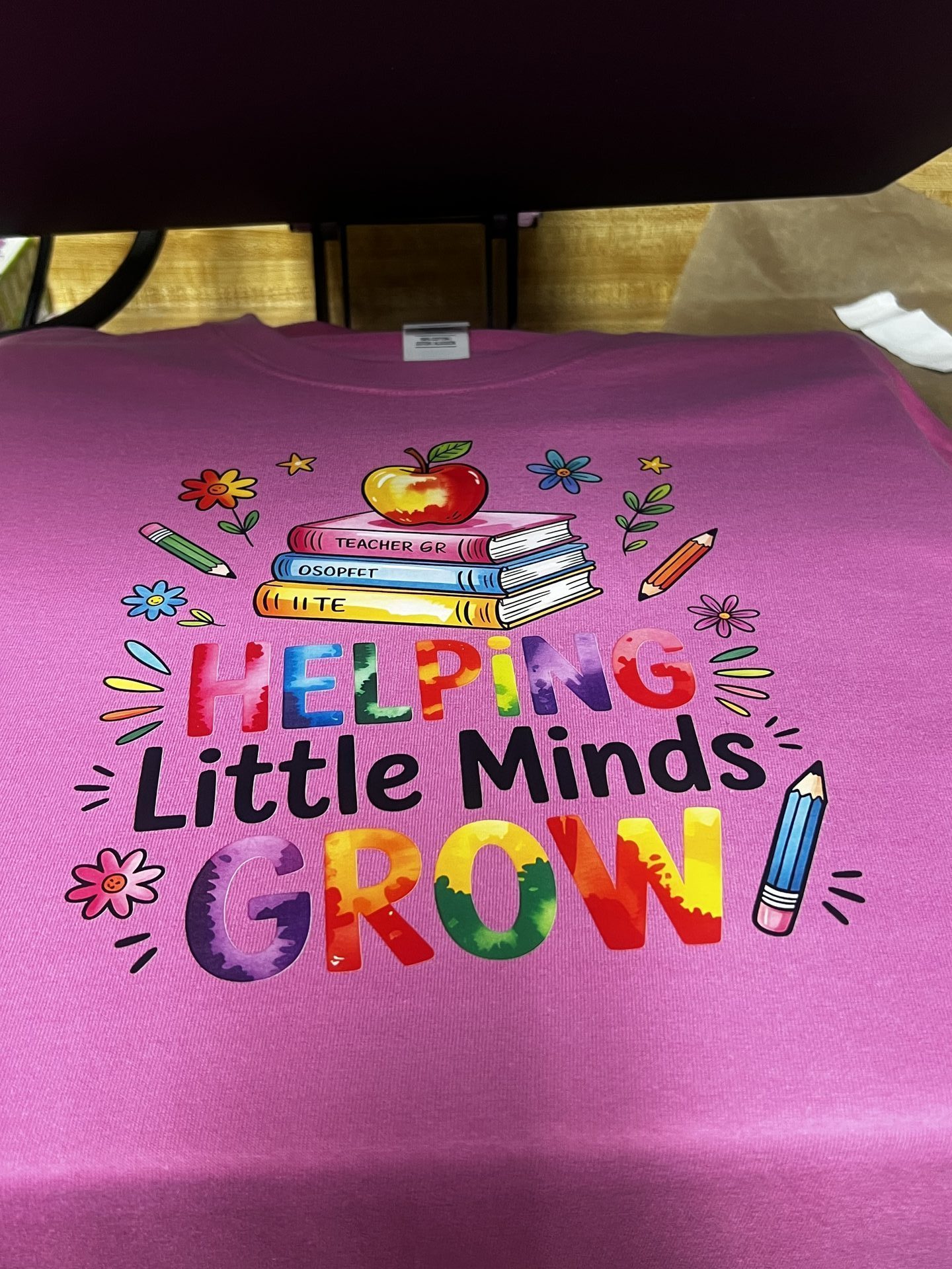 Custom pink shirt with Helping Little Minds Grow colorful typography